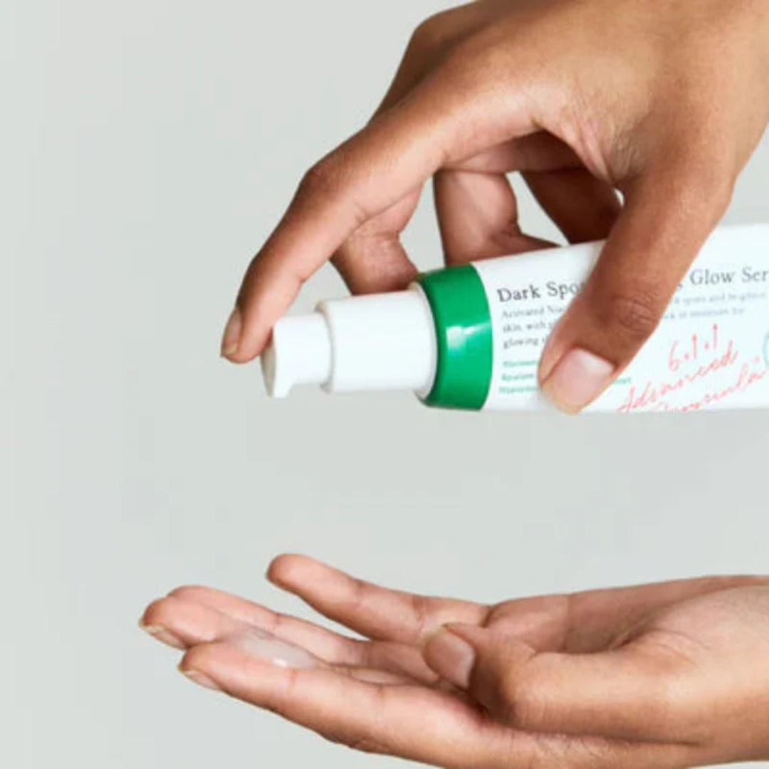 Hand holding a skincare serum bottle with a light gray background