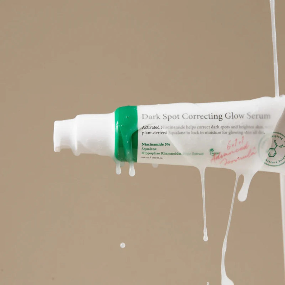 Tube of Dark Spot Correcting Glow Serum with green label on a beige background