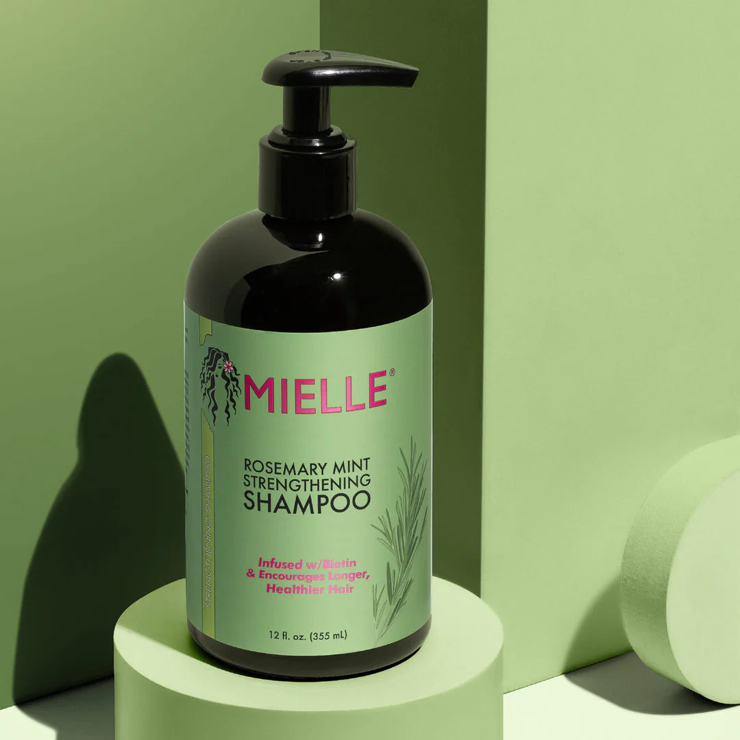 Mielle Rosemary Mint Strengthening Shampoo bottle on a green background