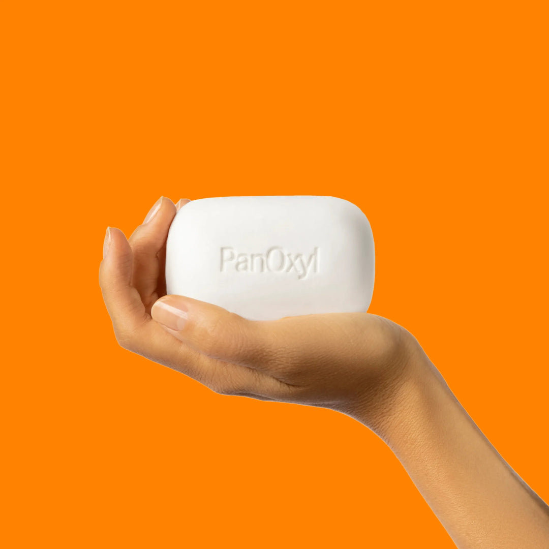 Hand holding a PanOxy bar against an orange background