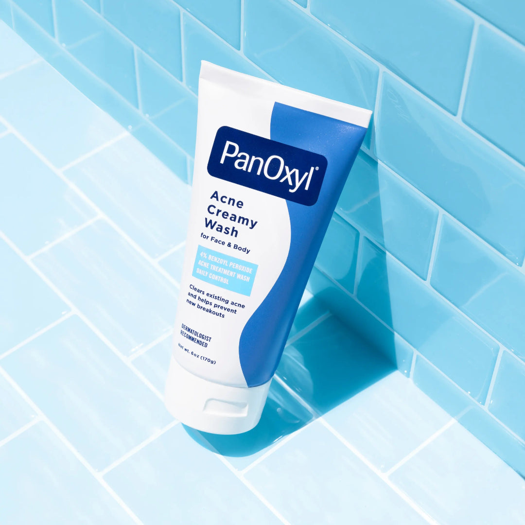 PanOxyl Acne Creamy Wash tube on a blue tiled bathroom floor