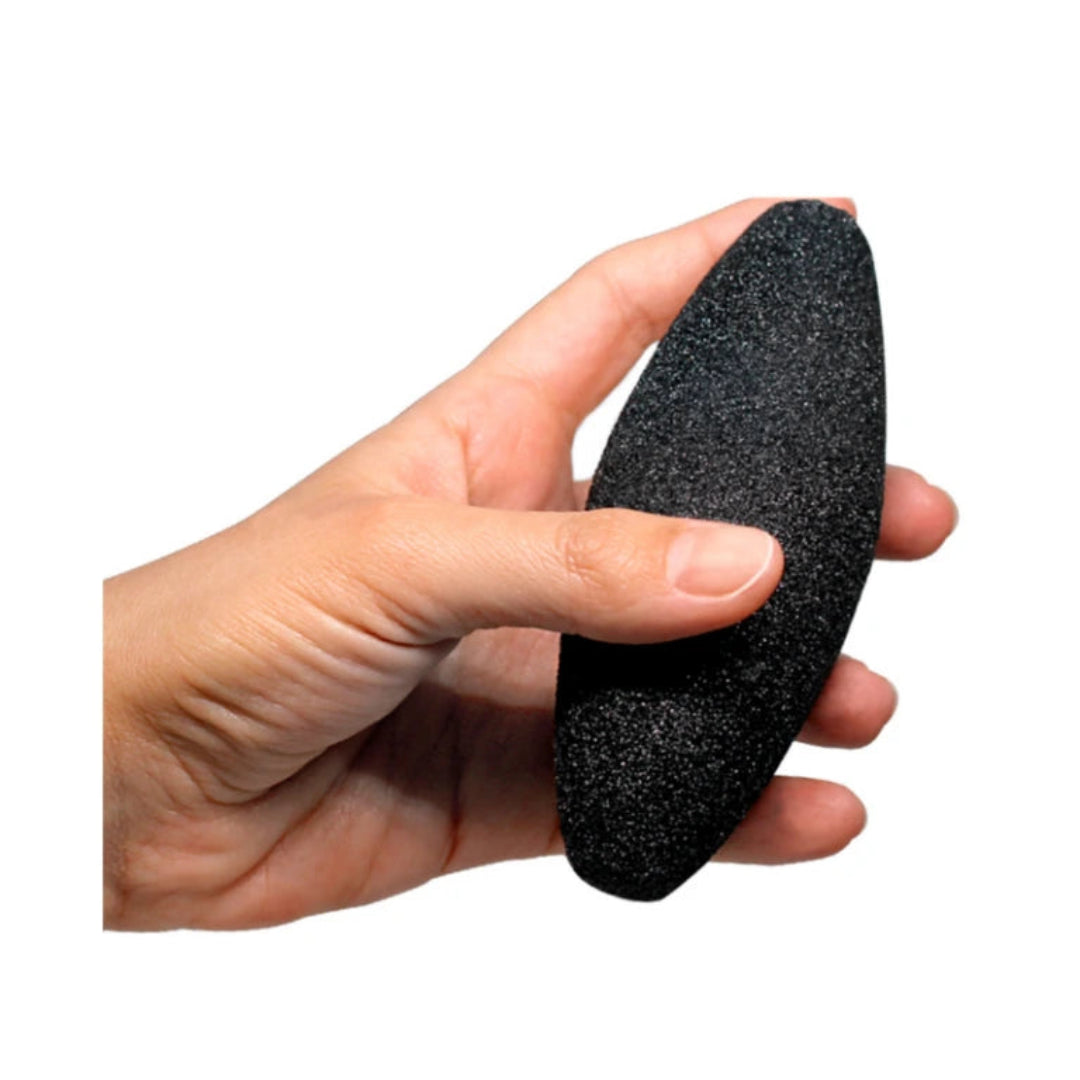 Hand holding a black pumice stone against a white background