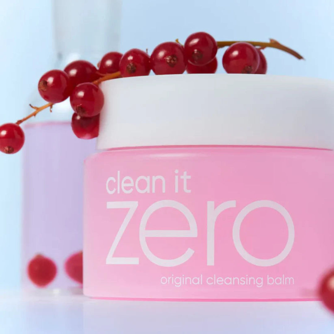 Pink cleansing balm container with red berries on a light blue background