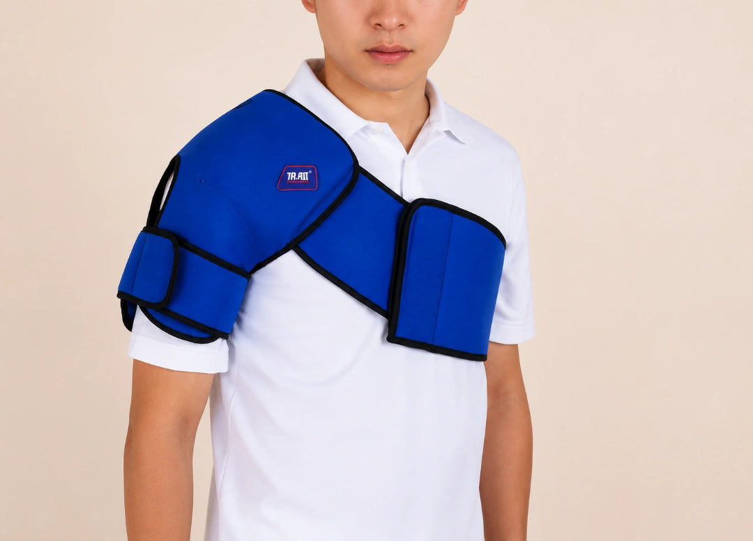 A man wearing a blue shoulder support brace over a white polo shirt, shown from the chest up against a plain beige background.